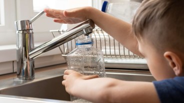 Un bambino raccoglie acqua dal rubinetto
