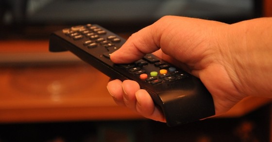 Un telecomando nero tenuto da una mano maschile