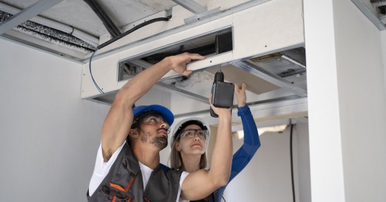 Due tecnici alle prese con l'installazione di un condizionatore