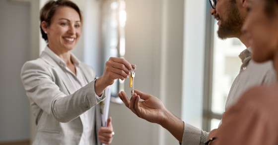 Agente immobiliare che consegna le chiavi della nuova casa a una coppia