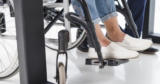 Piedi di donna disabile, sedia a rotelle, pavimento bianco