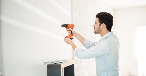 Un uomo pratica un foro su una parete