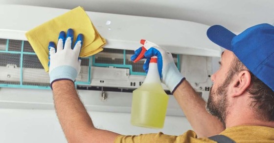 Tecnico in guanti gialli pulisce il condizionatore