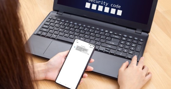 mani persona computer portatile con smartphone vicino tastiera richiamo OTP dello SPID