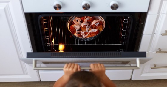 Bambina apre un forno con un dessert dentro