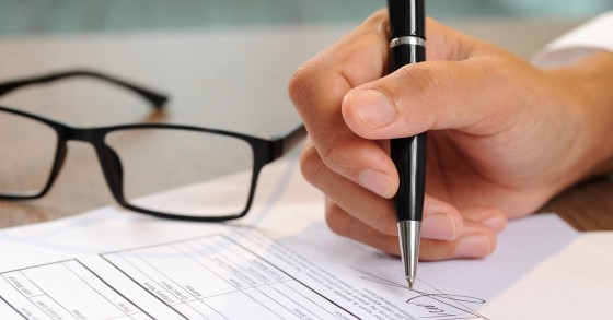 Primo piano di una mano che firma un documento 