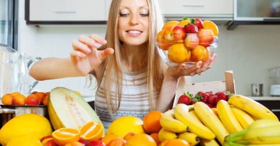 donna davanti a tavolo pieno di frutta 