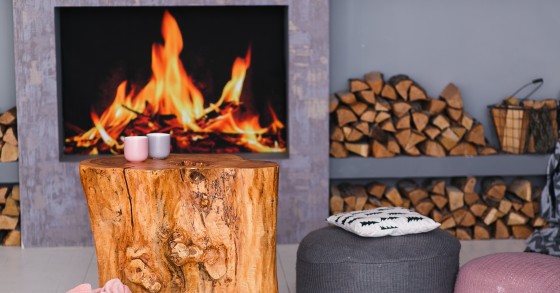 Interno in stile scandinavo con camino, tavolino ricavato da un ceppo e catasta di legna