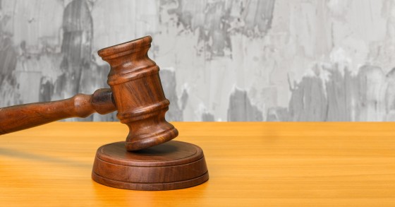 Martelletto di legno con sfondo di parete rovinata che illustra visivamente il classico caso di perizia per danni da infiltrazioni 