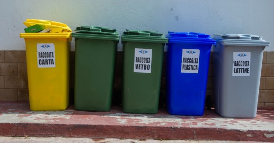 Cinque bidoni di riciclaggio colorati organizzati per la segregazione dei rifiuti in un contesto urbano
