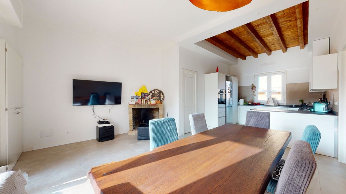 The kitchen/dining area with ceiling beams and a fireplace