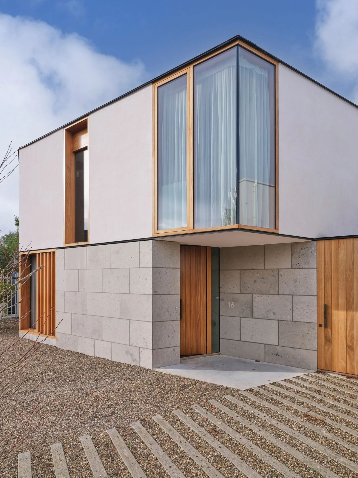 En la fachada principal se visualiza la combinación de los muros cortina con las superficies de estuco y revestimientos de piedra