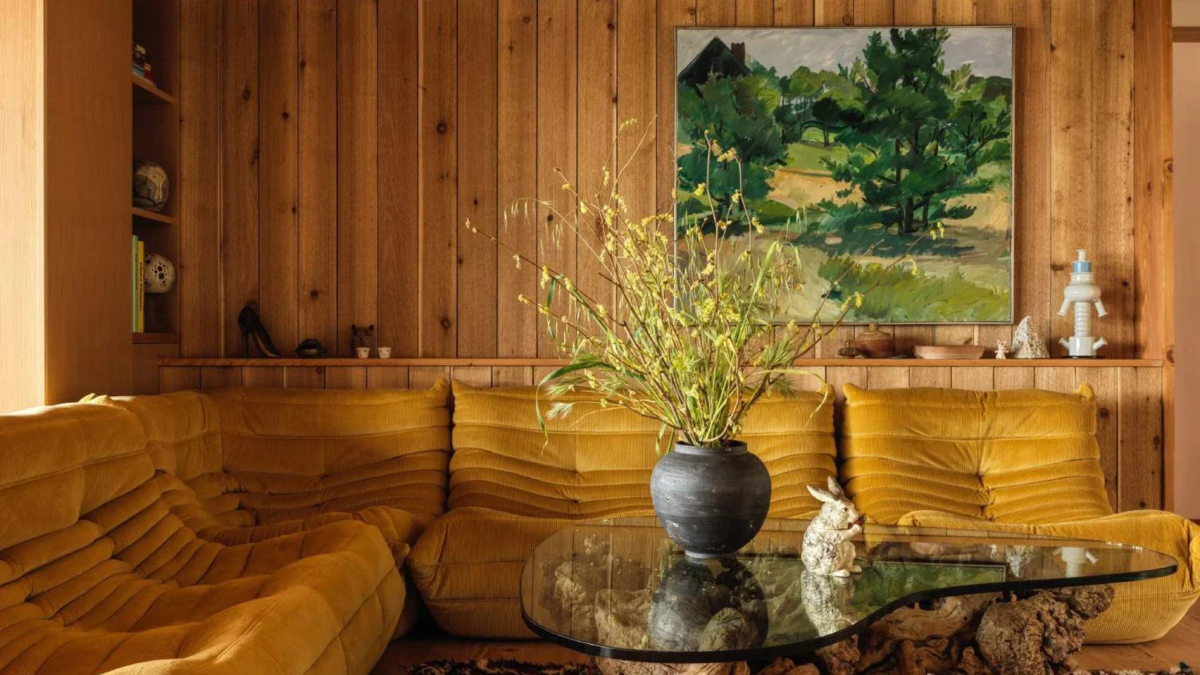 El salón está revestido de madera y cuenta con el clásico sistema modular de sofás Togo del diseñador Michel Ducaroy, envuelto en tela de pana amarilla.