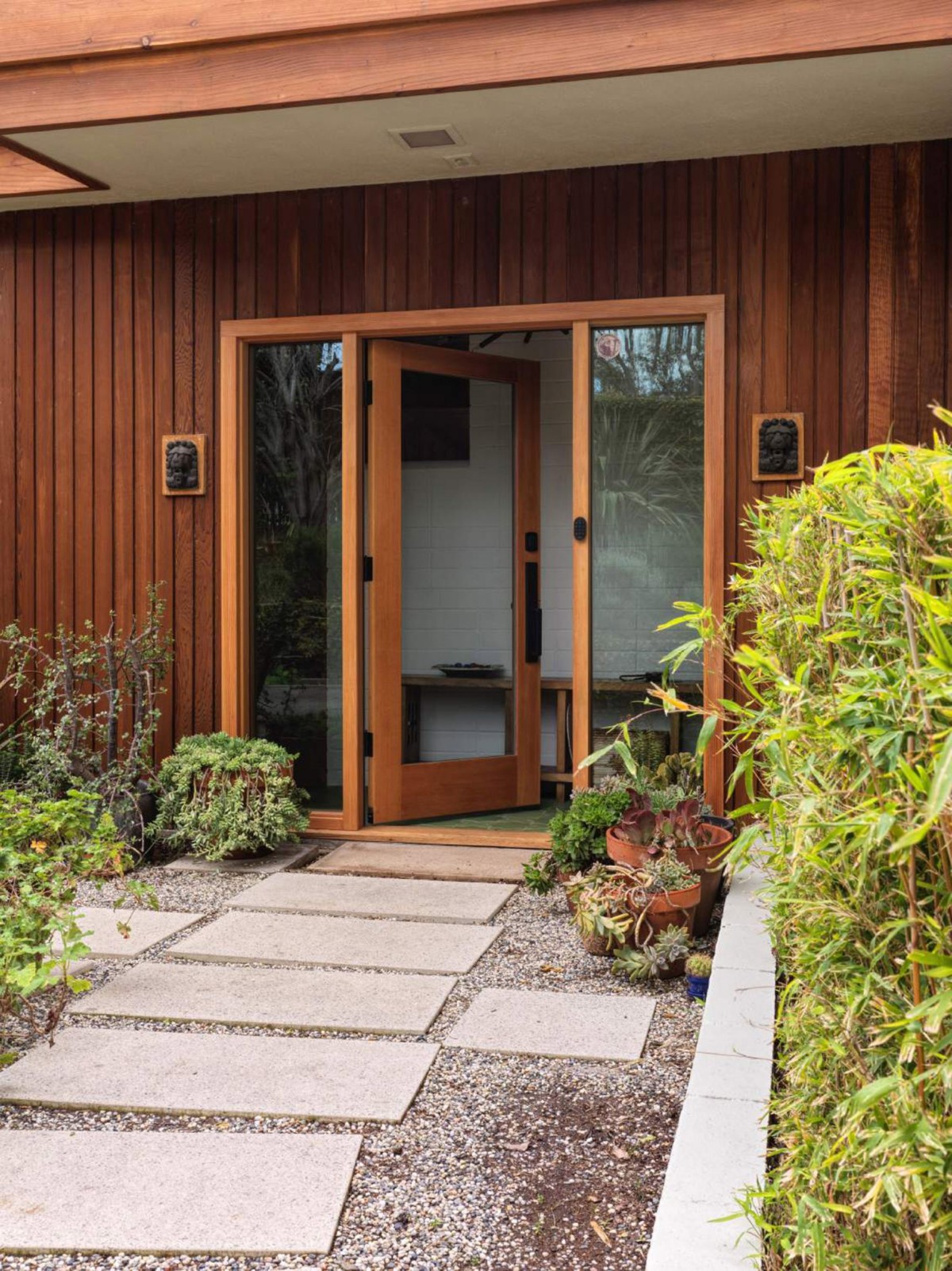 La entrada cuenta con grandes losas de piedra entre vegetación.