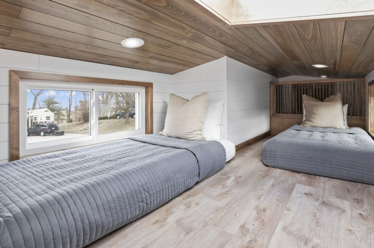 El dormitorio secundario está situado en un altillo accesible, ofreciendo un espacio íntimo con capacidad para dos camas individuales.