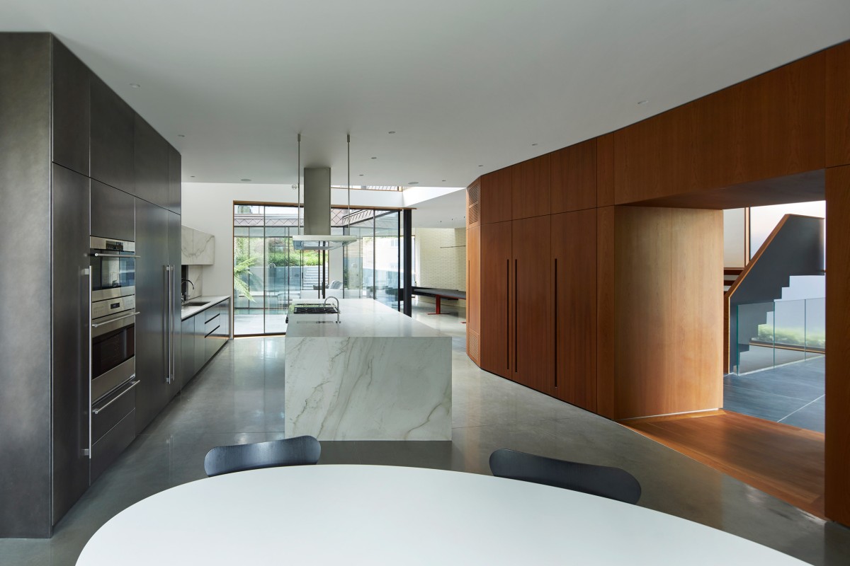 El diseño del espacio interior, con paredes blancas y una paleta de acabados en madera oscura y tonos grises y negros crea un ambiente moderno y sofisticado.