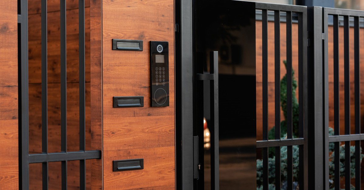 Un citofono nero con video in uno stabile a mattoni rossi con cancello nero