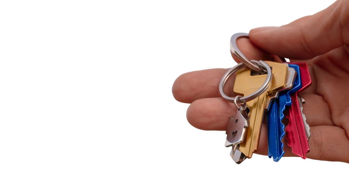 Mano che regge mazzo di chiavi colorate