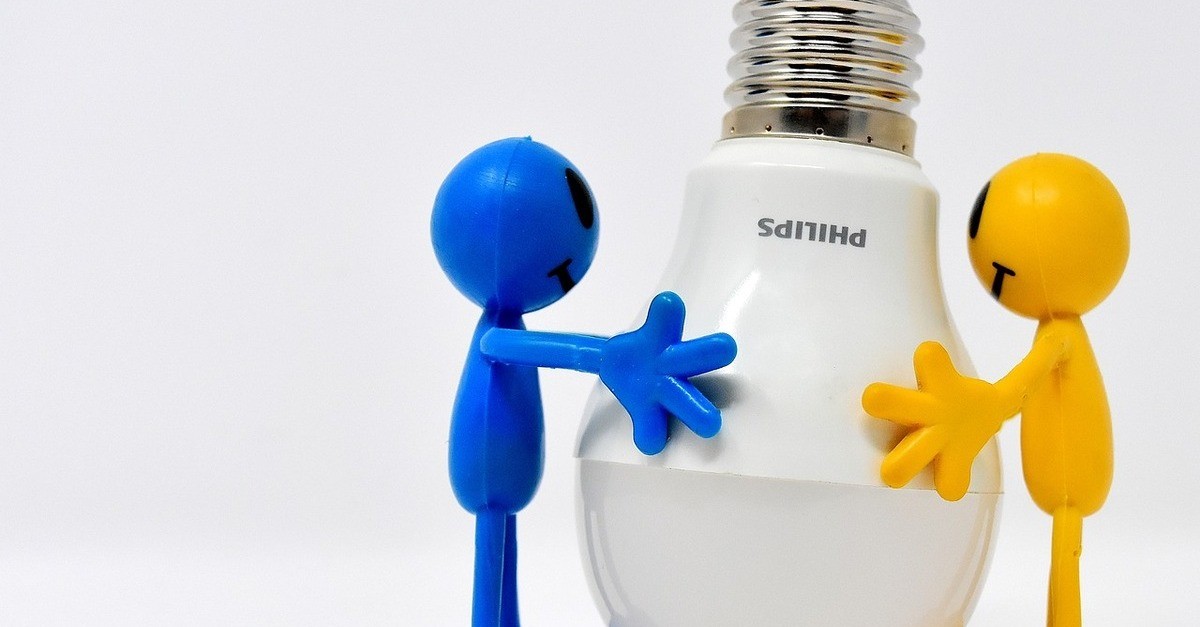 Una foto di due uomini stilizzati, uno blu ed uno giallo, che tengono tra le mani una lampadina