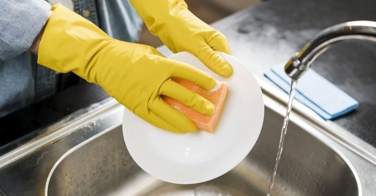 Persona lava i piatti con i guanti