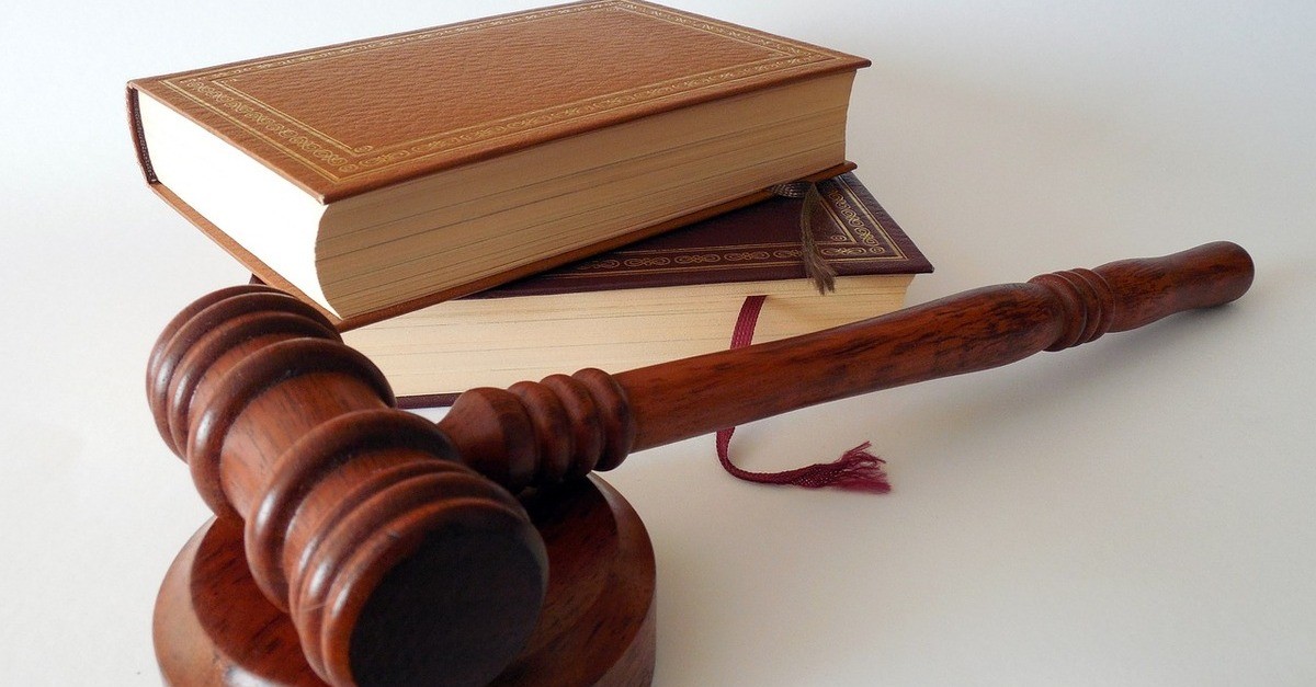 Un martelletto da giudice in legno marrone su un tavolo accanto ad un libro di legge