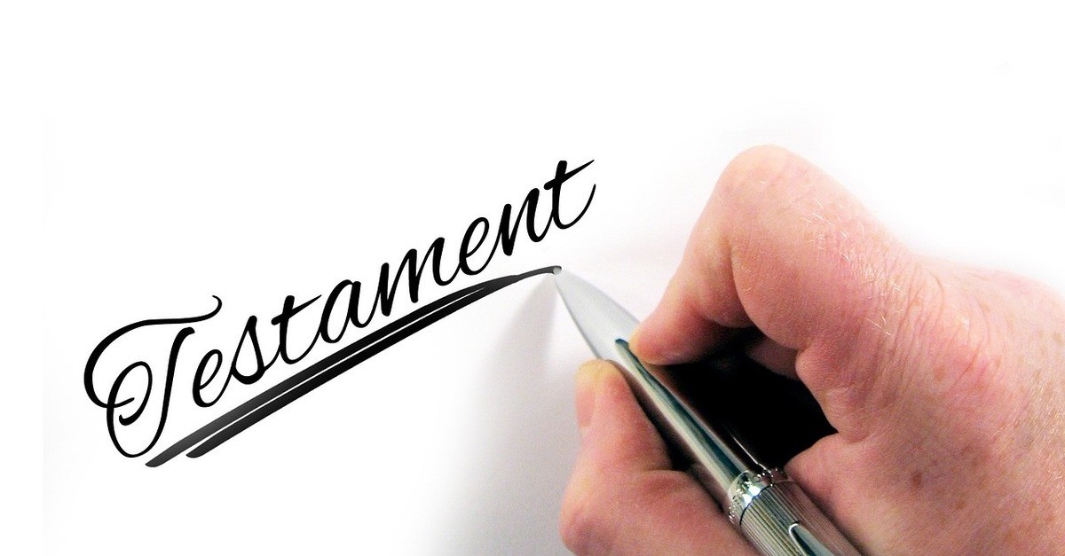 La foto di una mano con una penna che scrive la parola Testament