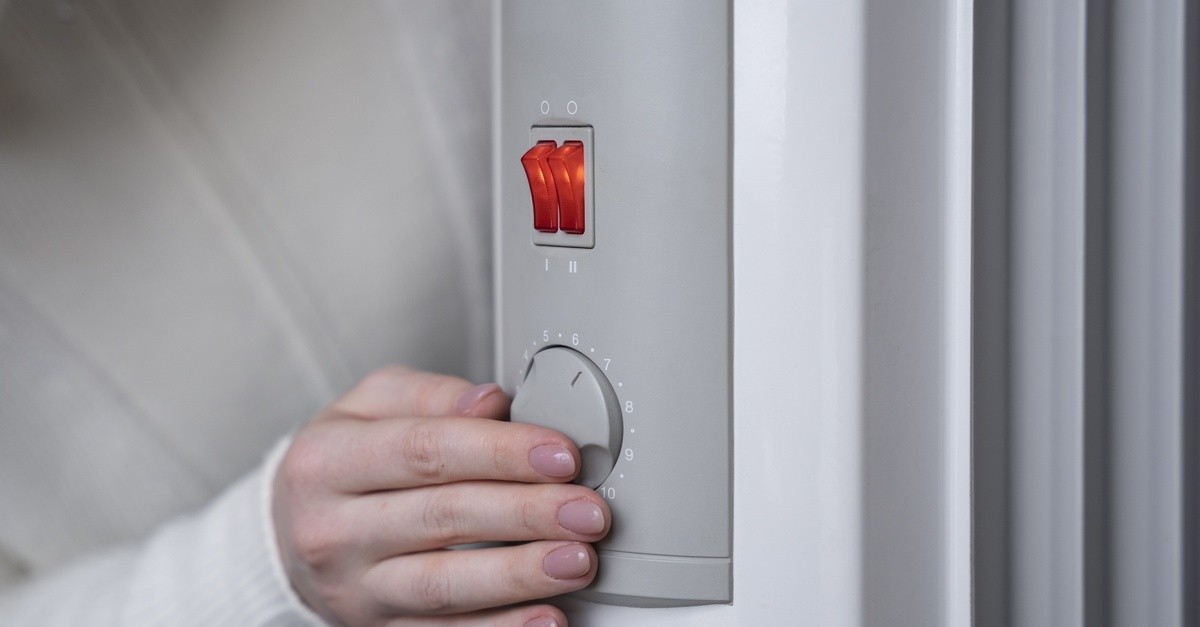 Una mano femminile con smalto rosa spegne un impianto di riscaldamento