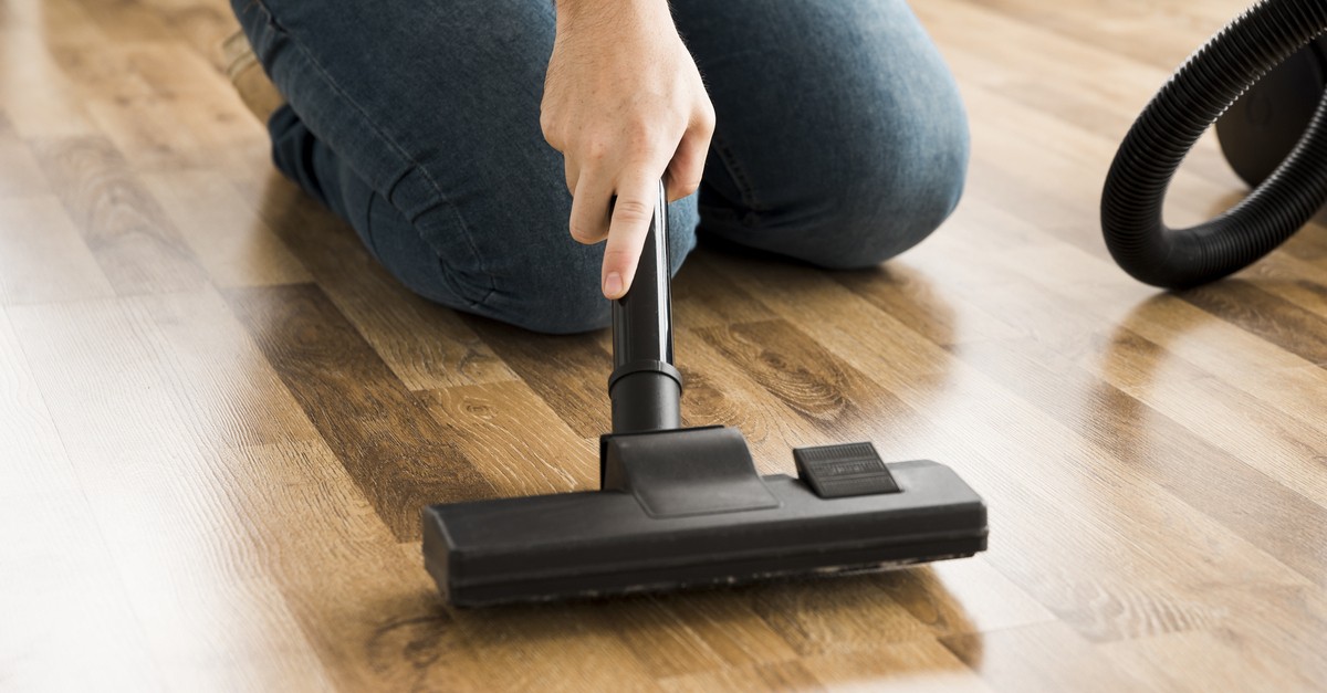 Aspirare la polvere da un parquet color miele 