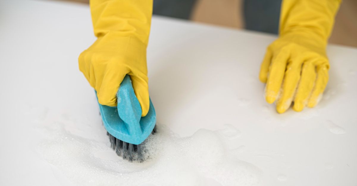 Persona che pulisce un materasso con una spazzola