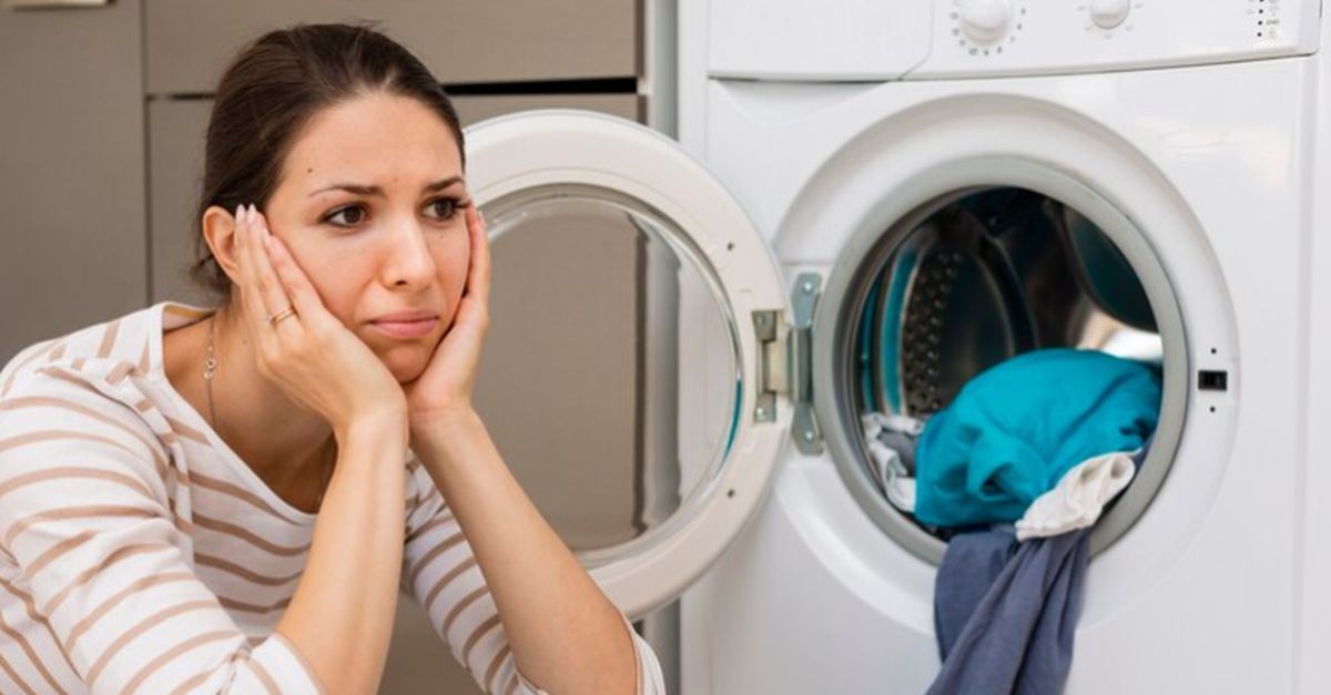 ragazza preoccupata davanti alla lavatrice