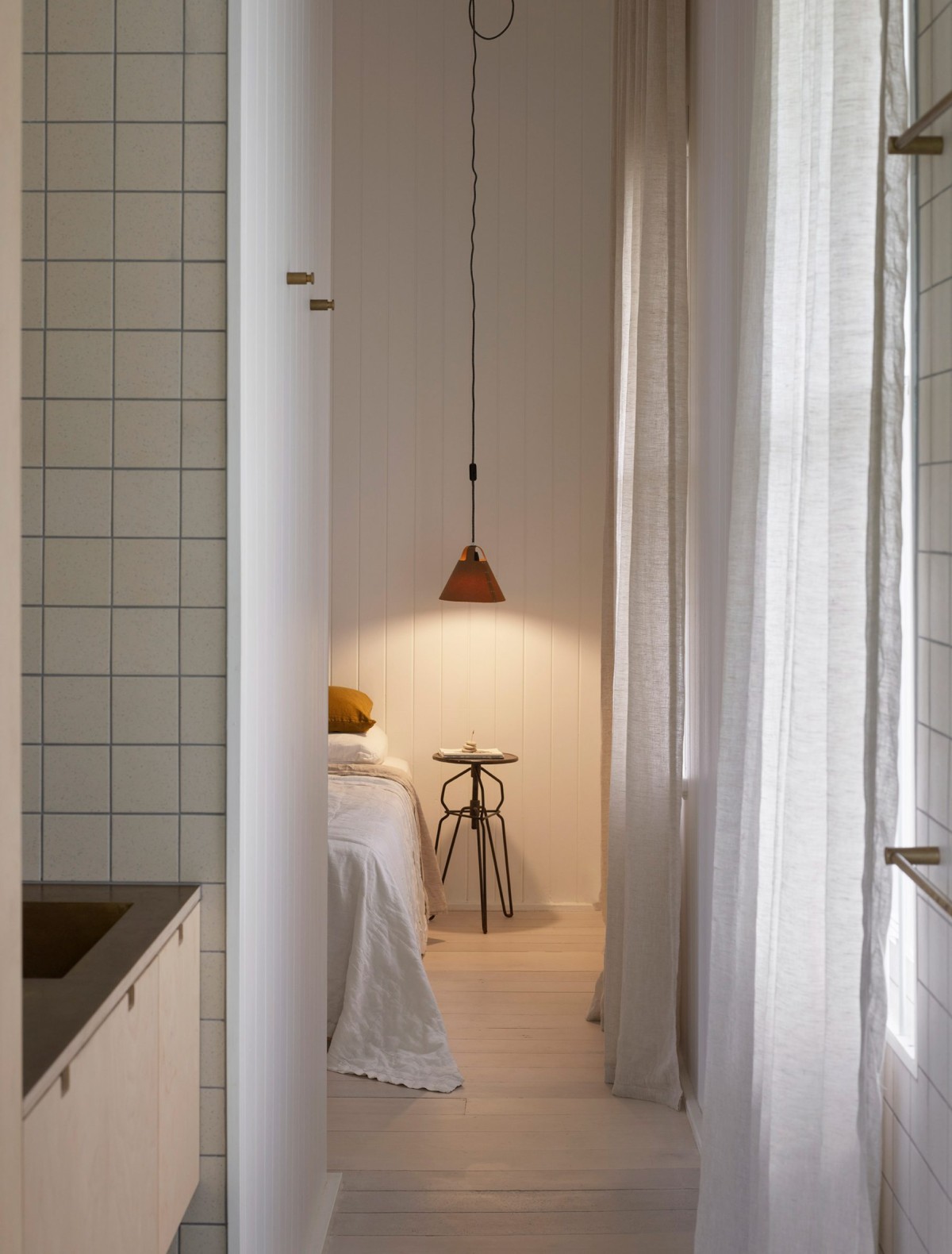 Los dormitorios están revestidos con superficies de madera pintada de blanco y techos altos que ayudan a iluminarlos.