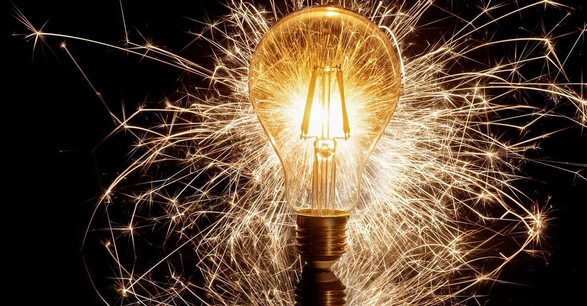 L' immagine di una lampadina accesa circondata da fili luminosi su sfondo nero