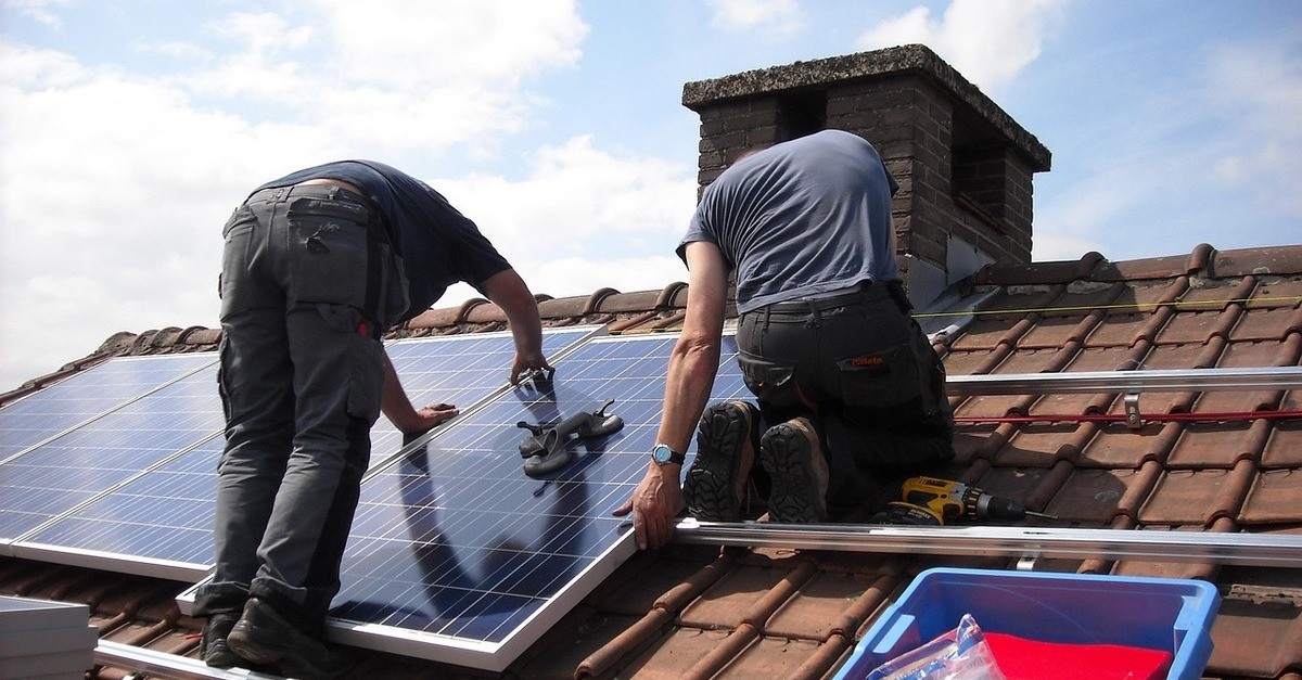 Due tecnici sul tetto stanno installando i pannelli solari Due tecnici sul tetto stanno installando i pannelli solari