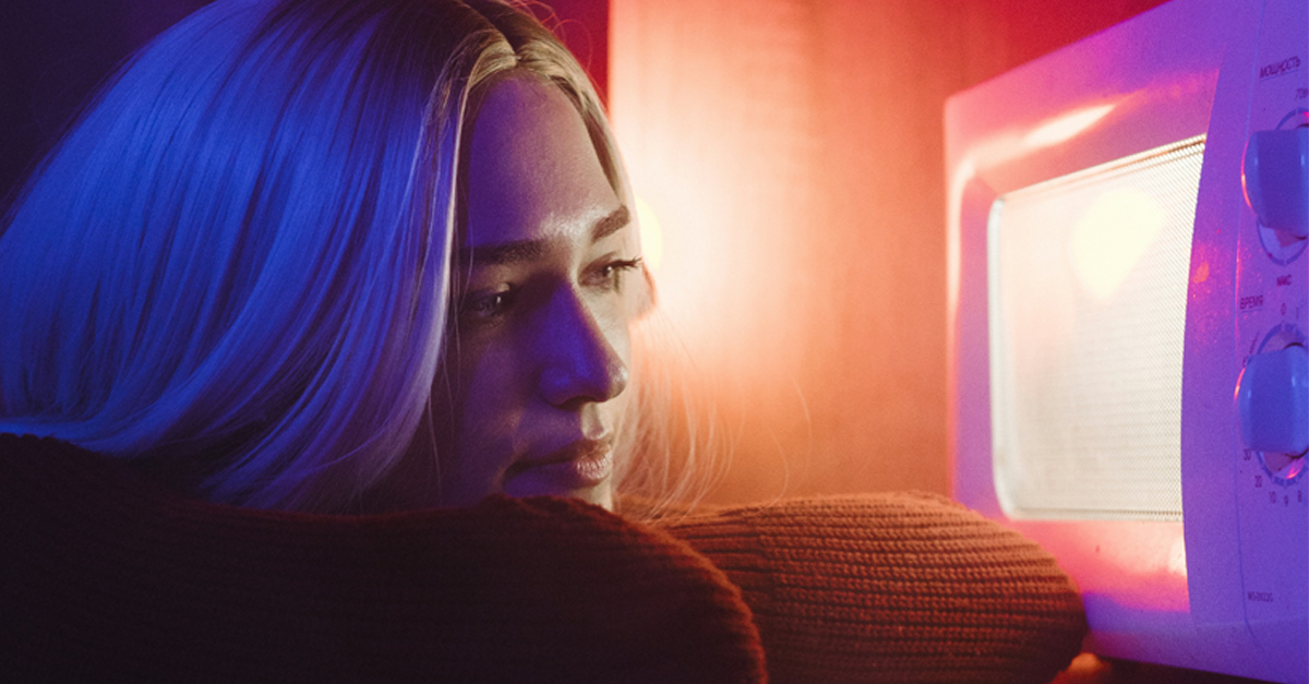 ragazza che guarda il microonde acceso