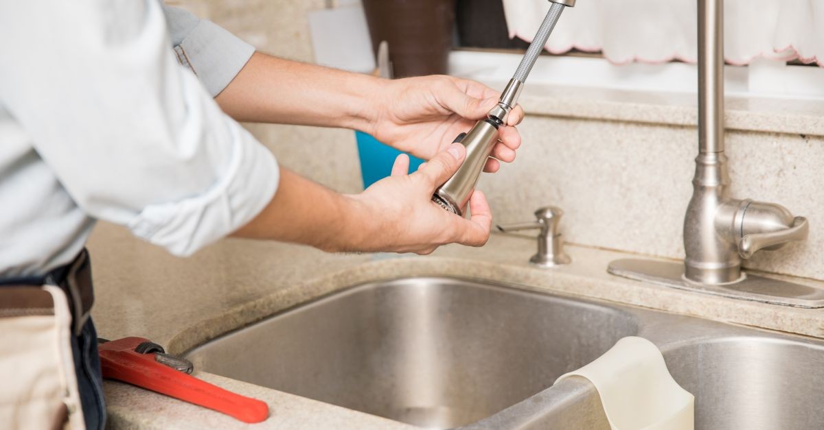 uomo che lavora sul rubinetto di una cucina