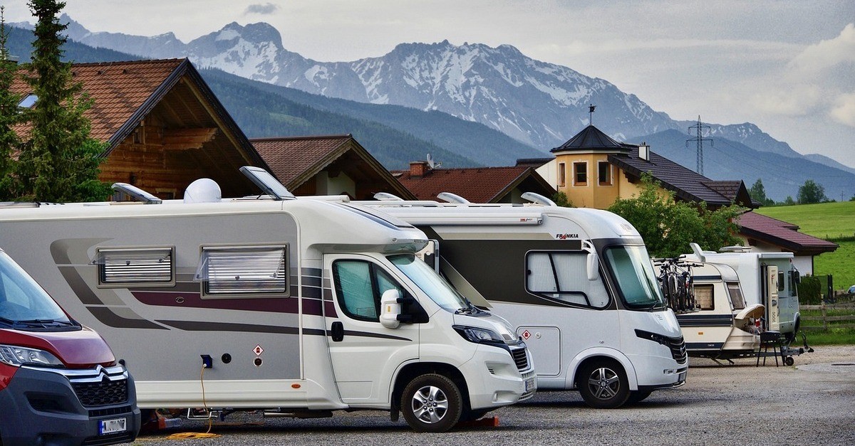 Due grandi camper parcheggiati in una zona libera con delle montagne sullo sfondo