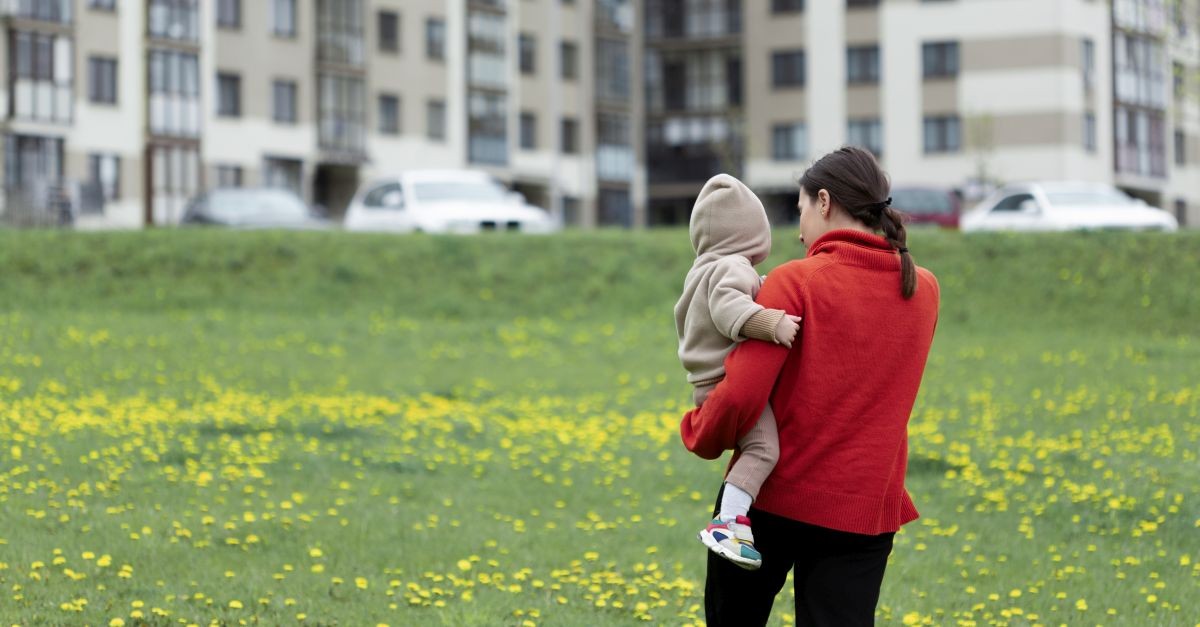 giovane madre con il figlio che passeggia nel prato davanti casa