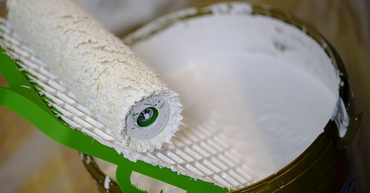 Pennello a rullo bianco con secchio di vernice