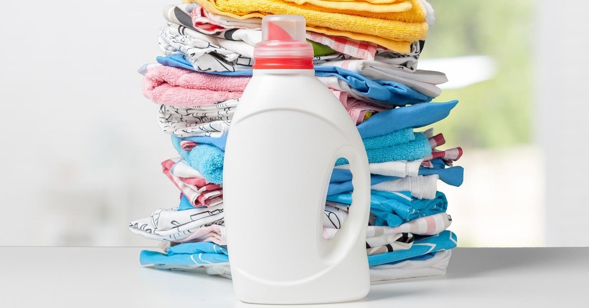 un flacone di candeggina davanti a una pila di biancheria