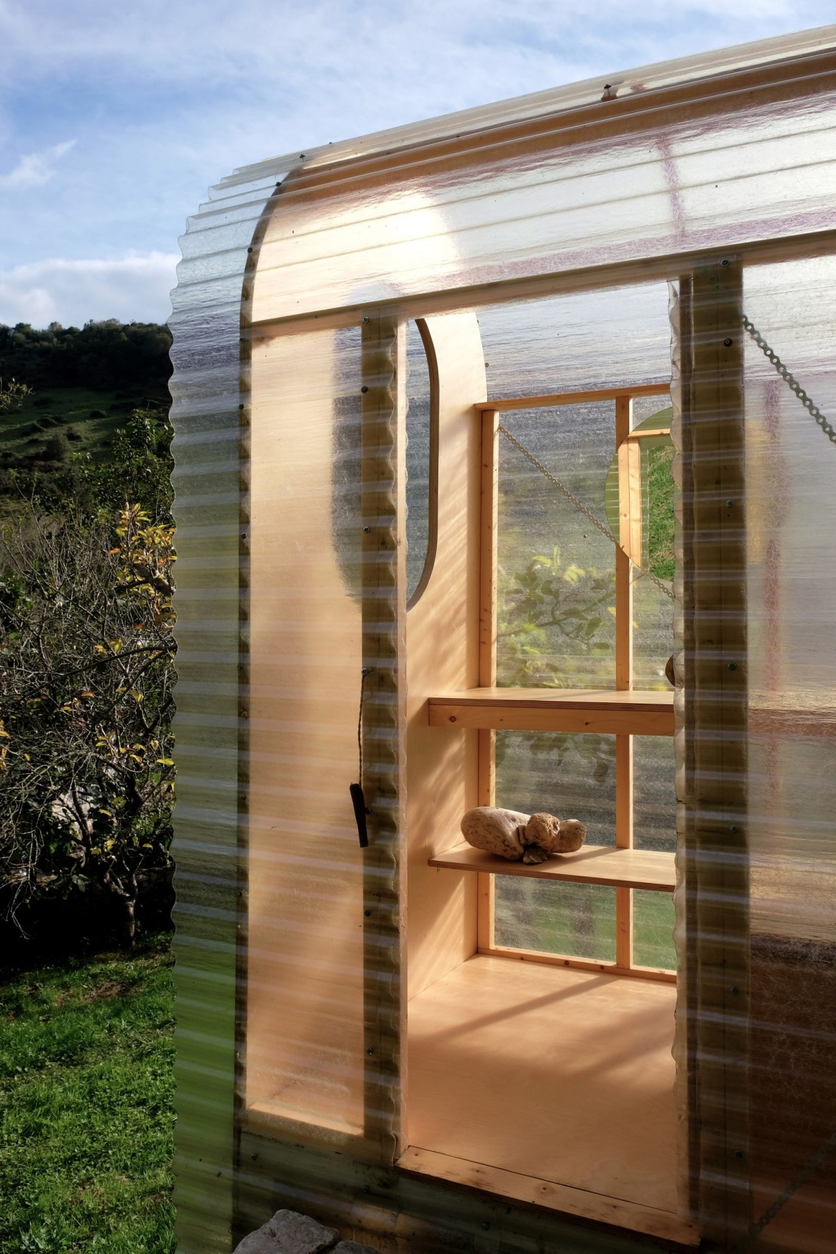 Las planchas de policarbonato se curvan suavemente alrededor de la estructura de madera.