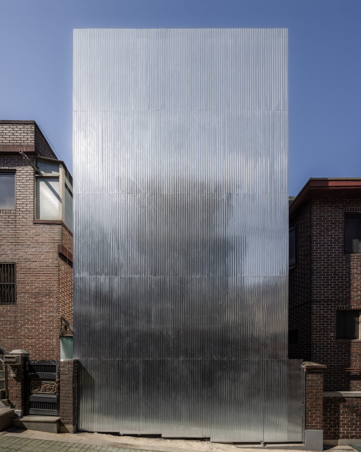 La fachada sin ventanas se compone por una serie de tablones de acero ligero ondulado.
