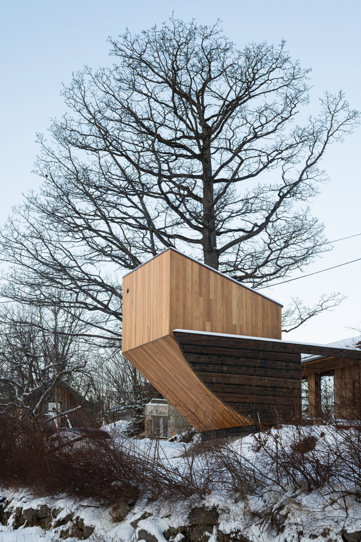 Desde la residencia principal, la nueva construcción aparece como la proa de un barco detenido en mitad de un jardín.