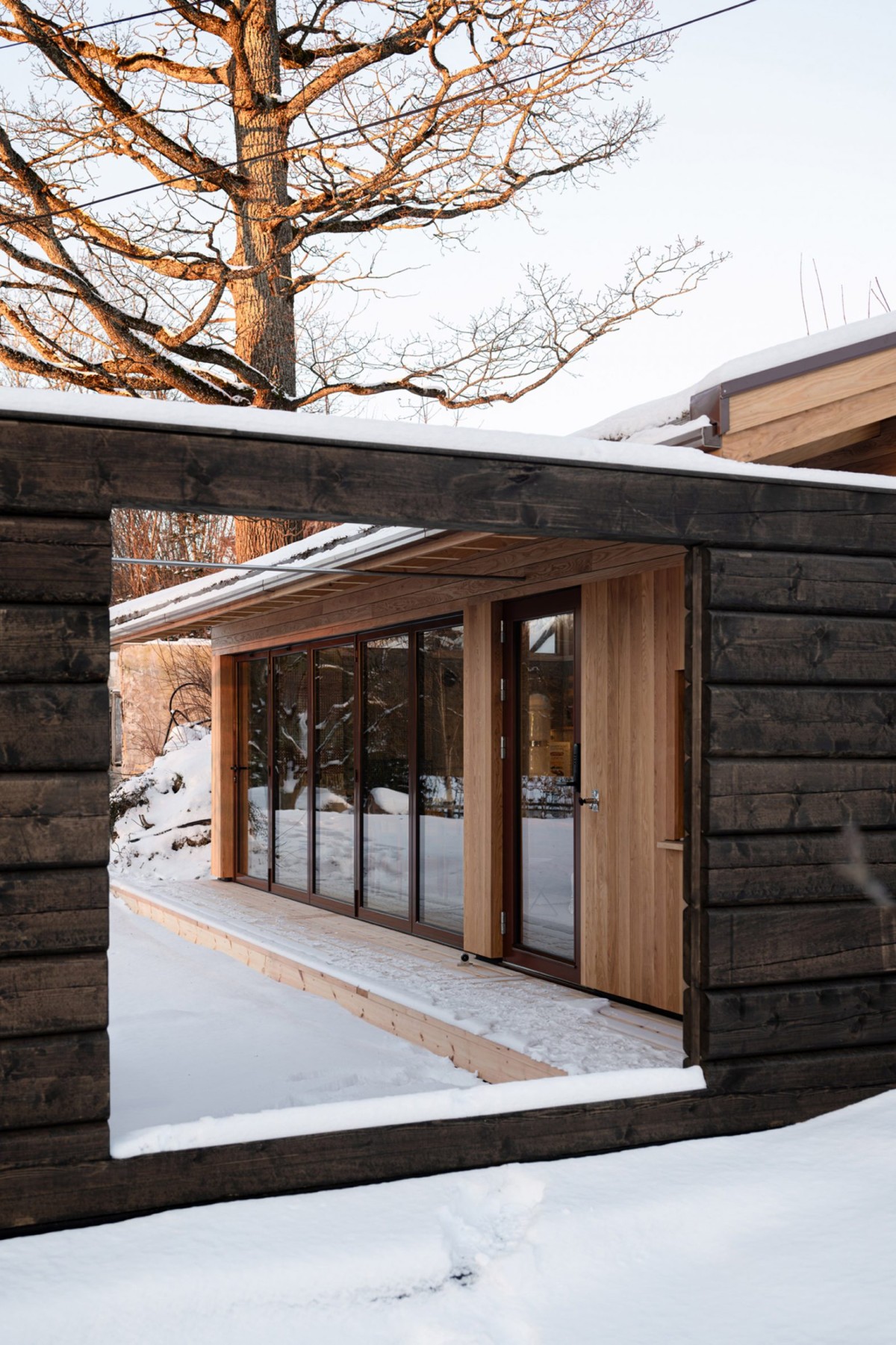 El acceso desde la “quilla” del barco contrasta entre los troncos de la puerta de la locura y la estructura revestida de roble del edificio principal.