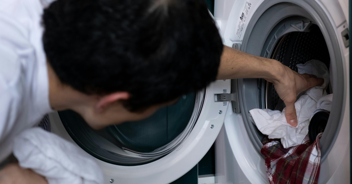un uomo mette i panni in lavatrice