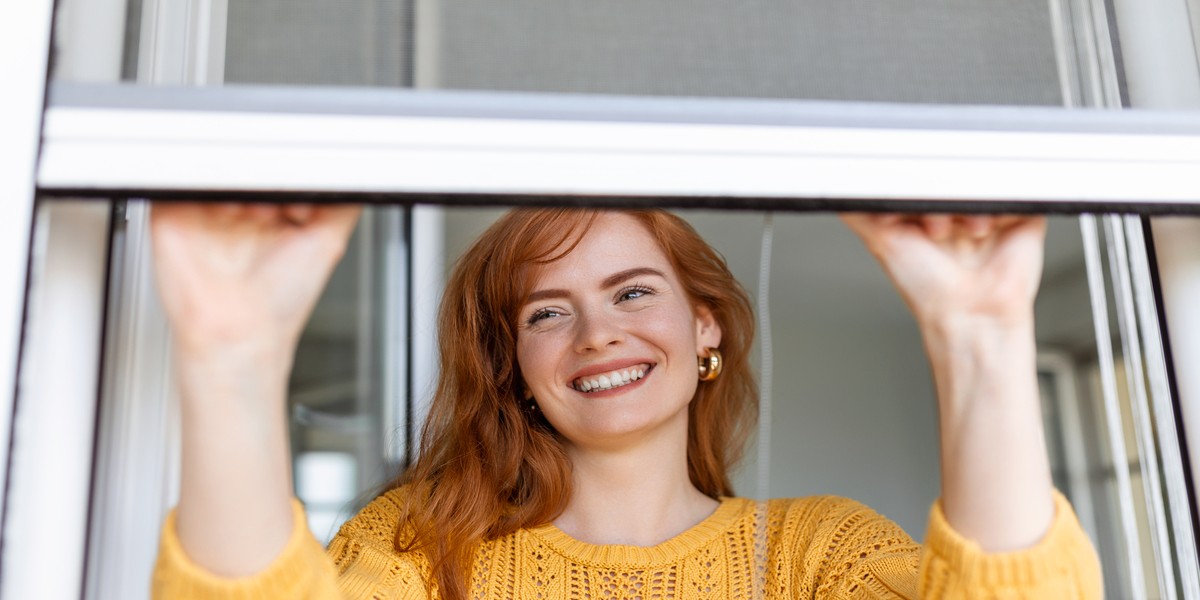 porta zanzariera plissettata scomparsa con presa mano da donna per aprire o chiudere le zanzariere della finestra