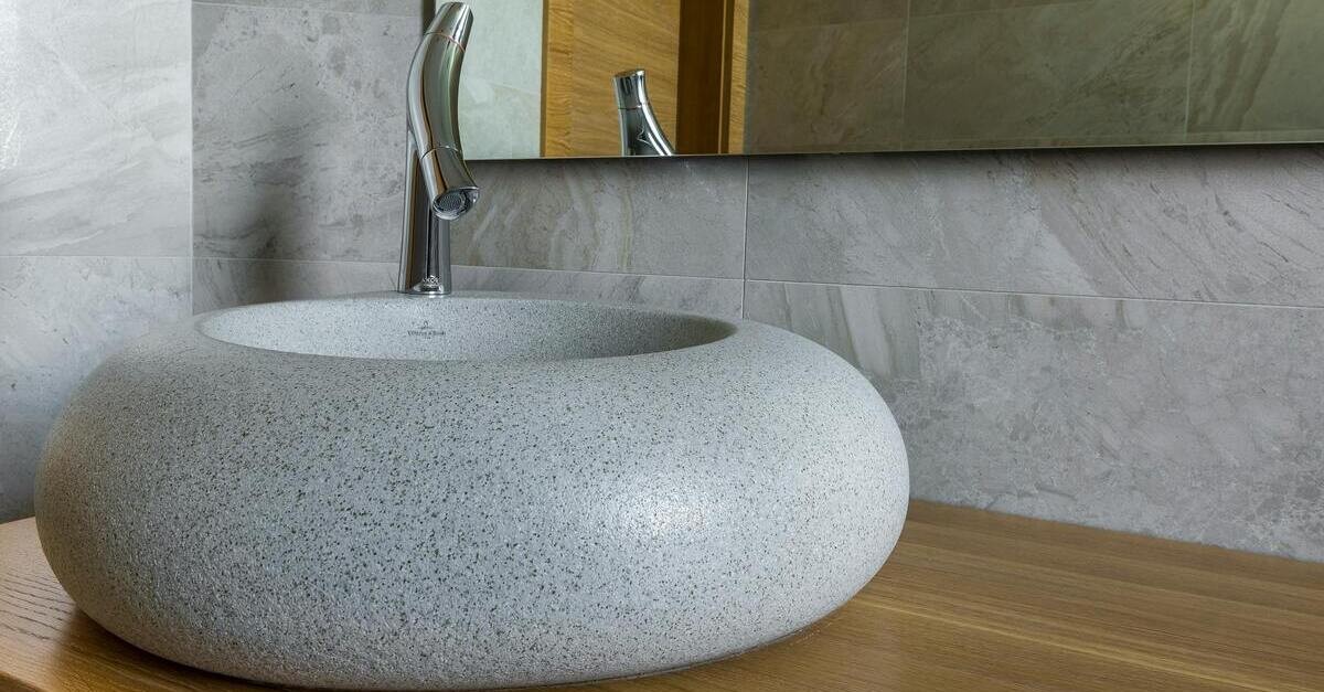 Un lavandino tondo di pietra chiara con venature scure