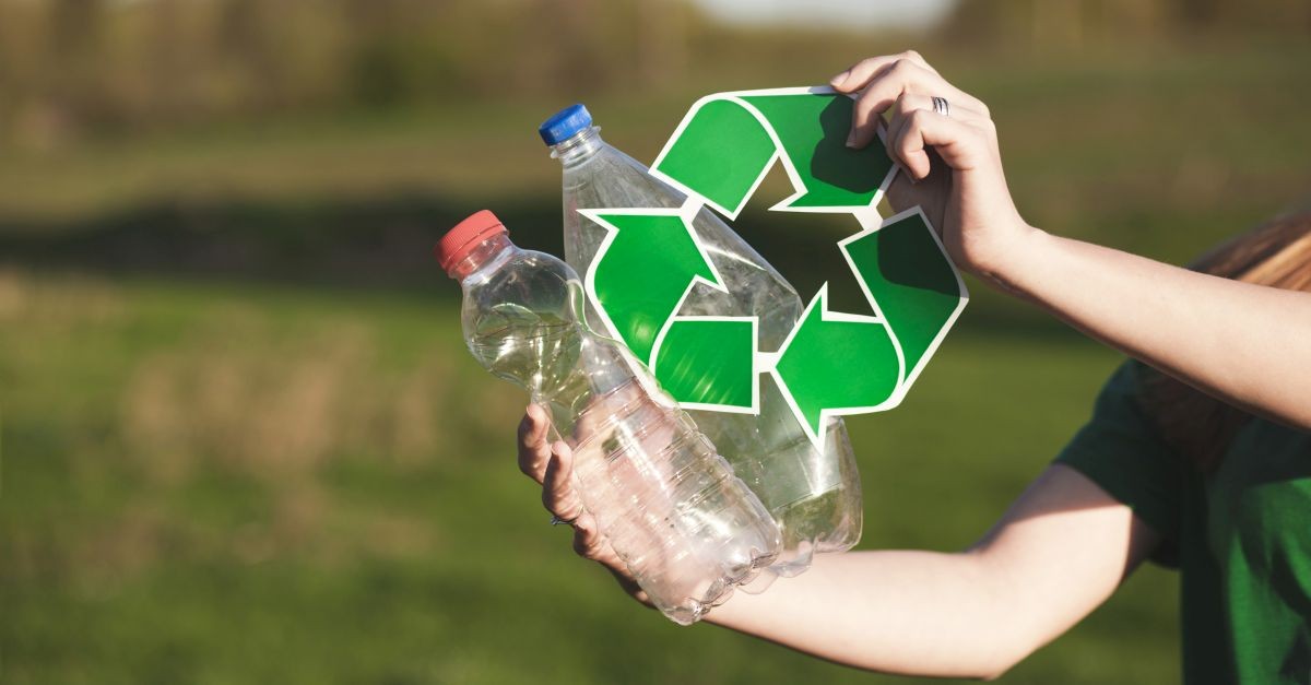 mano femminile che regge bottiglie di plastica e simbolo del riciclo