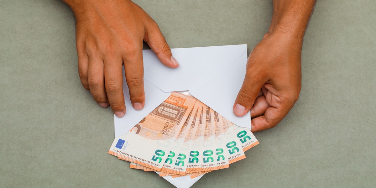 hombre sosteniendo un sobre lleno de billetes