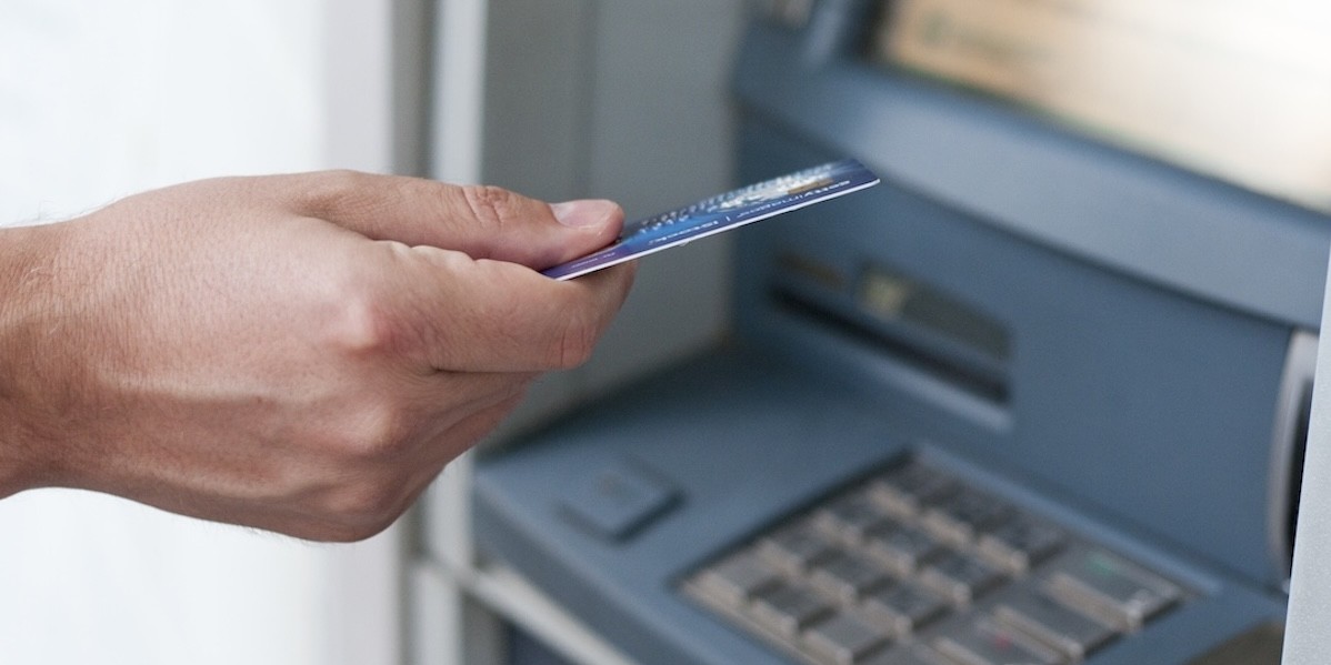 Mano che inserisce bancomat per prelevare