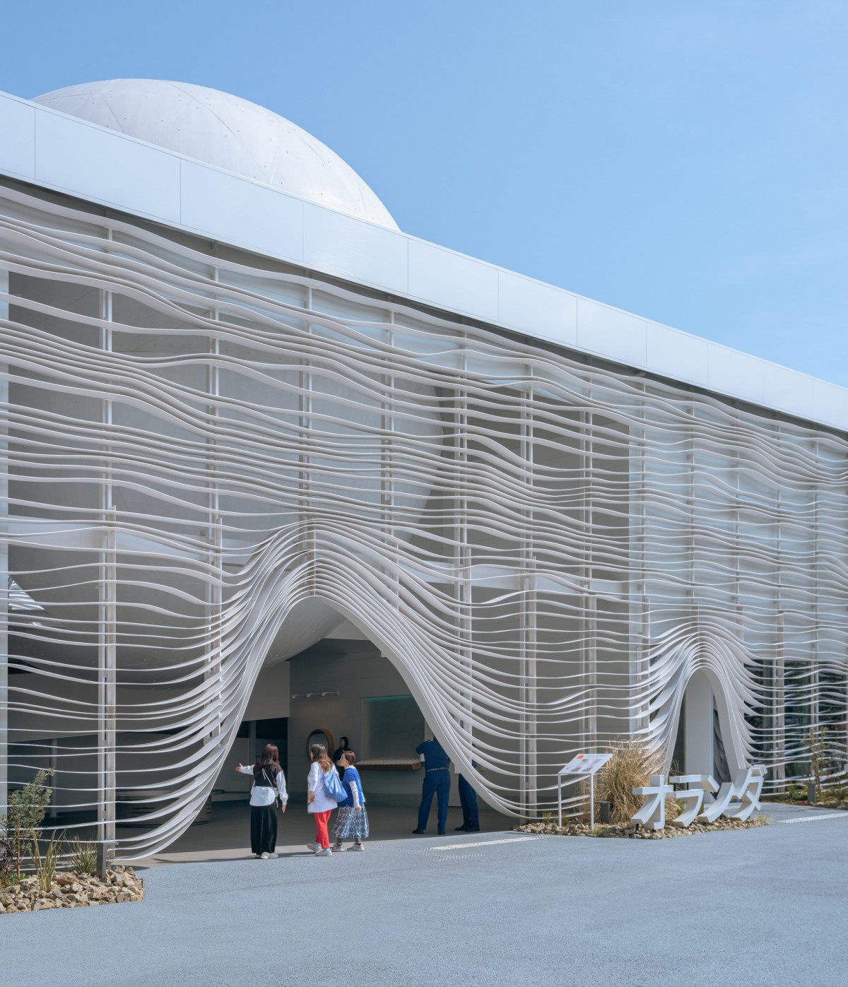 La struttura del padiglione è realizzata in acciaio, avvolta da listelli ondulati che creano un gioco dinamico tra monumentalità e leggerezza